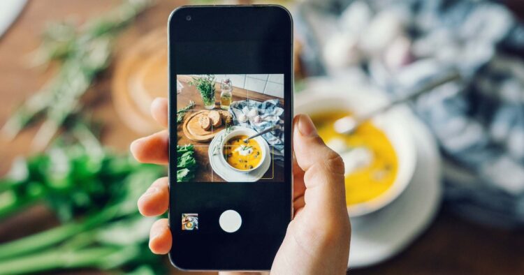 Woman taking photo of pumpkin soup with smartphone